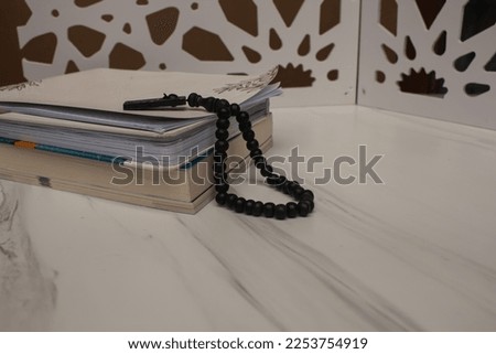 pile of books and black prayer beads on it against a white background