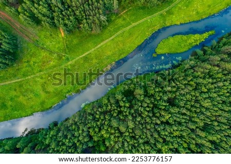 the river is located diagonally in the forest on a summer day. top view from a drone to the river and forest area. summer landscape of the river, the banks are covered with grass