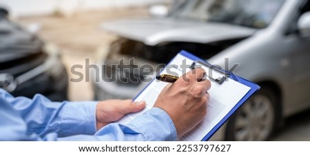 Insurance officer writing Insurance Claim Report on clipboard while insurance. Man and Insurance agent claim process after car crash 