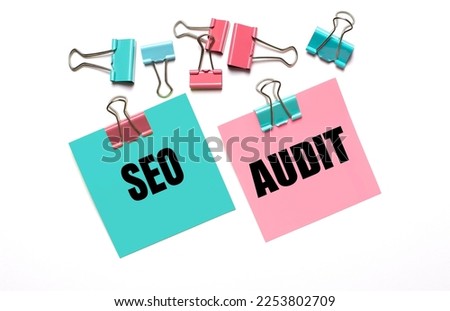 Colorful stickers with SEO AUDIT text and multicolored paper clips on a white background