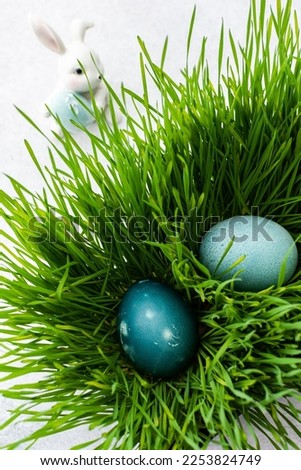 Colorful Easter eggs in the grass and cute bunnies, searching for eggs on Easter day, top view, copy space