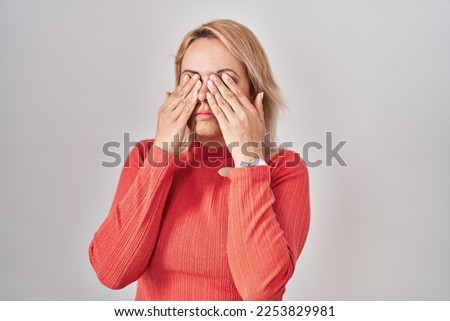 Blonde woman standing over isolated background rubbing eyes for fatigue and headache, sleepy and tired expression. vision problem 