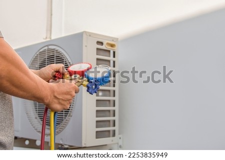 Air conditioning, HVAC service technician using gauges to check refrigerant and add refrigerant. Royalty-Free Stock Photo #2253835949