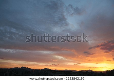 The beautiful sunset sky is spread out and the skyline of the city and mountains is shown in silhouettes