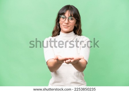 Young caucasian woman over isolated background holding copyspace imaginary on the palm to insert an ad Royalty-Free Stock Photo #2253850235