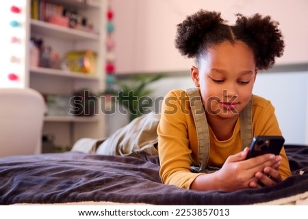 Girl Lying On Bed At Home Looking At Social Media On Mobile Phone Royalty-Free Stock Photo #2253857013