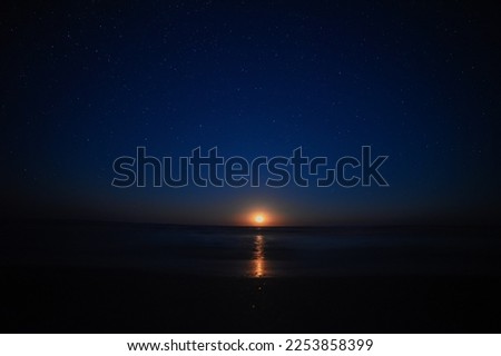 Moon rise by the sea with sky full of stars. Amazing orange moon is rising up. Nature astronomy night landscape.