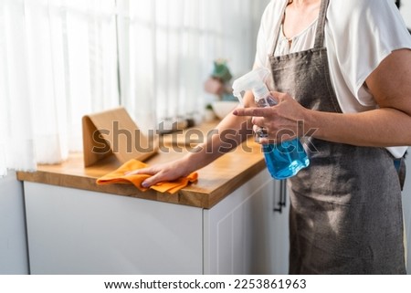 Caucasian senior elderly woman wearing apron, cleaning kitchen at home. Attractive mature old housekeeper cleaner feel tired and upset while wiping dining table for housekeeping housework or chores.
 Royalty-Free Stock Photo #2253861963