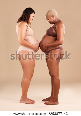 Two women, pregnant and belly touch in studio for support, bonding and friends by background. Young future mother, pregnancy and happy with solidarity, diversity and care for wellness, health or hope