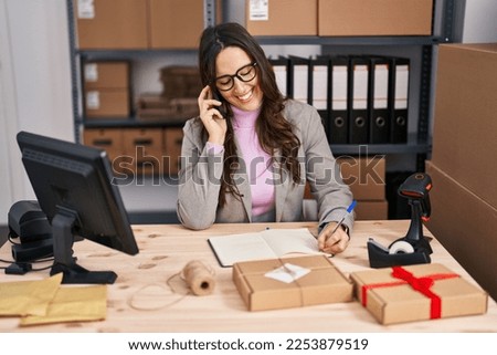 Young hispanic woman ecommerce business worker talking on the smartphone at office