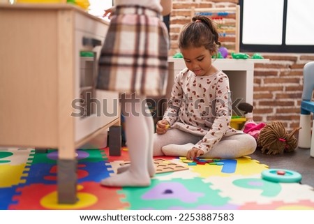 Two kids playing with play kitchen and maths puzzle game at kindergarten
