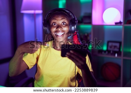 African american woman playing video games with smartphone smiling happy pointing with hand and finger 
