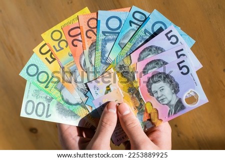 Paying cash with Australian dollars, showing each denomination of the Australian dollar bills, loan and bribery concepts. Royalty-Free Stock Photo #2253889925
