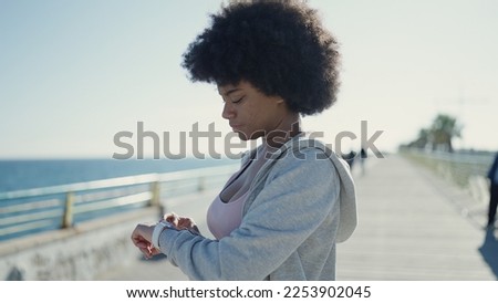 African american woman using stopwatch standing at seaside