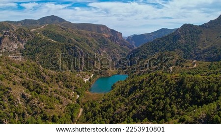 High mountain lagoon next to the valley and mountainous landscape with colorful sky. Granada. Spain.