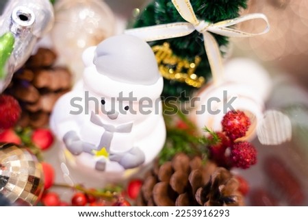 A white snowman with a Christmas tree and a unicorn in a glass jar under soft light.