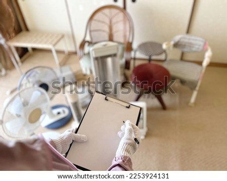Gloved hand holding a clipboard in front of many chairs and electrical appliances Royalty-Free Stock Photo #2253924131