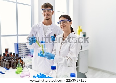 Man and woman partners wearing scientist uniform holding test tube at laboratory Royalty-Free Stock Photo #2253939123