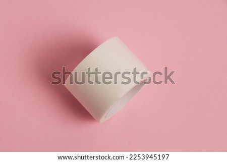 White medical patch on a paper base, for applying bandages, on a pink background.