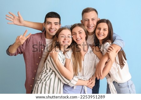 Group of happy friends hugging on blue background