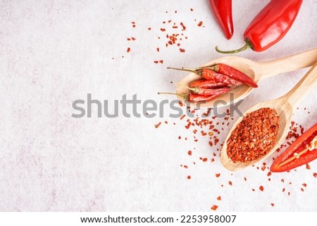 Spoons with chipotle chili flakes and dried jalapeno peppers on light background Royalty-Free Stock Photo #2253958007