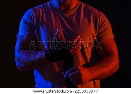 Silhouette of muscular young man with athletic tape on black background, closeup