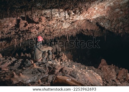 a caver sitting and looking at the cave formations surounding him Royalty-Free Stock Photo #2253962693