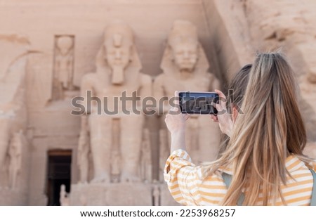 Unrecognizable young ponytail woman taking a picture of the beautiful monument and ancient temple of Abu simbel in Egypt Royalty-Free Stock Photo #2253968257