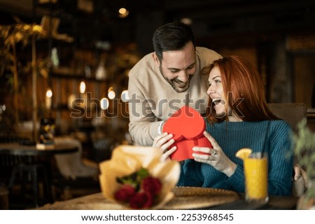 Valentines day couple sitting in favourite caffe, exchanging gif