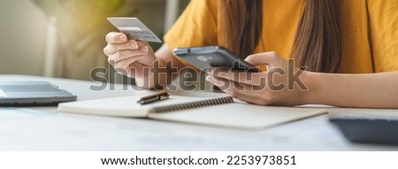 Close up view hands of young woman holding a credit card and doing bank transactions via mobile phone application at home