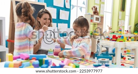 Teacher with girls sitting on table having emotion therapy at kindergarten