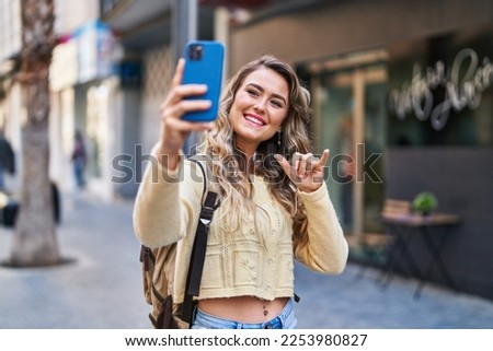 Young woman tourist making selfie by the smartphone at street