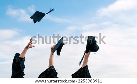 Three graduating students hands throwing graduation caps in the air. Royalty-Free Stock Photo #2253983911