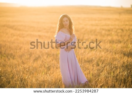 portrait of a happy young girl in a dress in a wheat field at sunset, the concept of peace and unity with nature. High quality photo