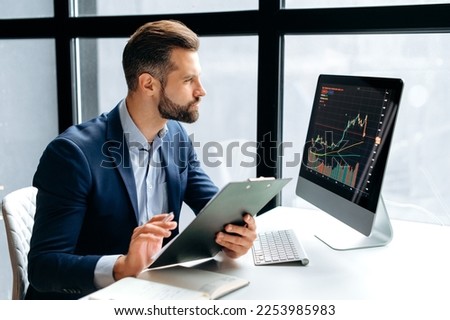 Thoughtful focused successful caucasian male stock investor, broker, financial adviser, sits at work desk, looks at computer, pensively analyze risks and prospects, rise or fall of cryptocurrency coin Royalty-Free Stock Photo #2253985983