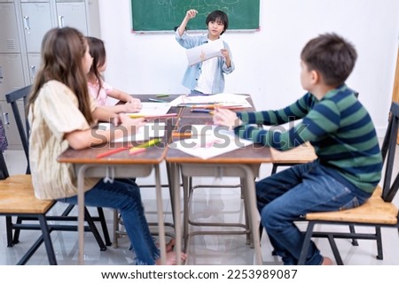 Children in class room happy laughing enjoy draw picture on paper and show to friend
