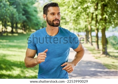 Handsome young man running in park during spring summer Royalty-Free Stock Photo #2253990029