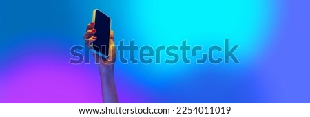 Cropped image of female hand holding mobile phone over gradient blue background. Online communication, remote work. Banner. flyer. Cocept of modern technologies, network, education, information