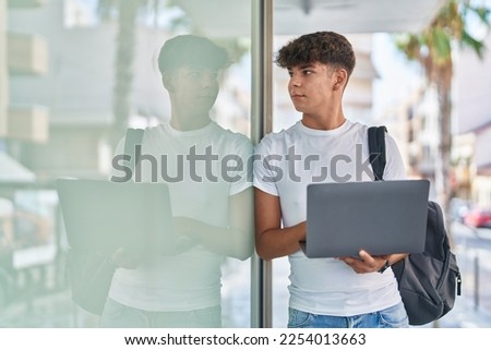 Young hispanic teenager student using laptop with relaxed expression at university