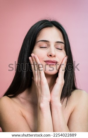 woman with makeup touching cheeks applying cream on face