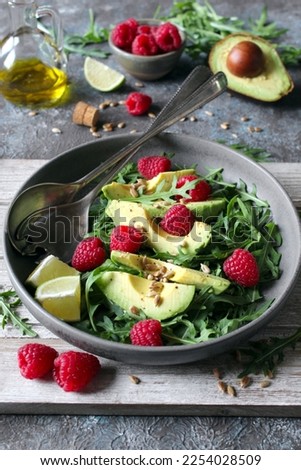 Avocado salad with arugula, raspberries and sunflower seeds. Top view.