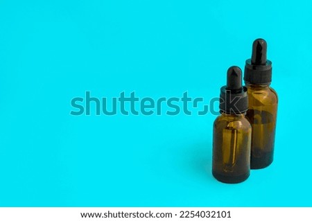 Glass vials on a blue background. Brown glass vials with a pipette on a blue background.