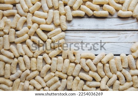Lots of yellow corn sticks lying on a white wooden background in the shape of an oval. Delicious airy dessert. Concept and picture, copy space. Baby food.
