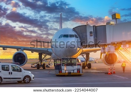 Airplane execute push back operation at airport. Aircraft service for flights before departure in the evening at sunset Royalty-Free Stock Photo #2254044007