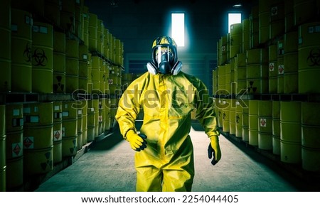 Man in mask and yellow protective clothing walks inside a slag storage site. Royalty-Free Stock Photo #2254044405
