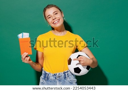 Traveler happy young woman fan wear basic yellow t-shirt cheer up support football sport team hold soccer ball pasport ticket isolated green background Tourist travel abroad in free time rest getaway Royalty-Free Stock Photo #2254053443