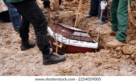 Burial. Men lower the coffin into the grave. Royalty-Free Stock Photo #2254059005