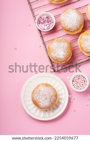 Happy National donut day or Valentines Day Concept. Donuts doughnuts with icing sugar and sugar sprinkles on pink background, copy space. Colorful carnival or birthday party card.