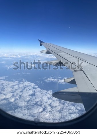 A beautiful picture of the sky from an airplane window! There are clouds and the sky is an elegant shade of blue.