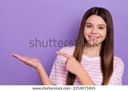 Photo of positive friendly person beaming smile direct finger hand hold empty space offer isolated on violet color background